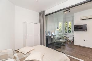 a white bedroom with a bed and a living room at Apartment Mille in Rijeka