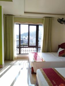 a bedroom with two beds and a large window at Tom's Family Hotel in Ha Long