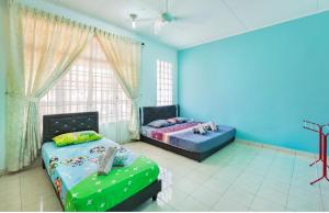 2 Betten in einem Zimmer mit blauen Wänden und einem Fenster in der Unterkunft Homestay Rini Zikry in Skudai