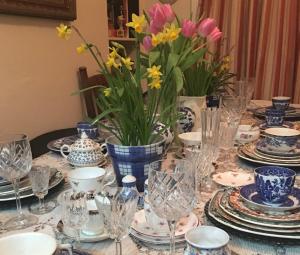 una mesa con platos azules y blancos y jarrones con flores en Wynberg House Bed & Breakfast, en Swansea