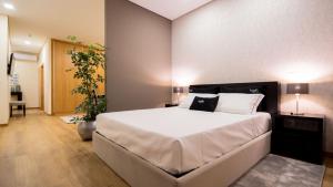 a bedroom with a large white bed and a plant at Bugalha My Loft Douro 9 in Peso da Régua