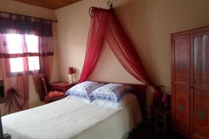Schlafzimmer mit einem Bett mit rotem Baldachin in der Unterkunft Chez Vivi in Ria