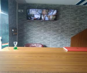 a television on a brick wall with a wooden desk at Ahlan Green Apple Dormitory in Mumbai