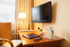 a room with a desk with a television on a wall at Hotel Senator Marina in Wedel
