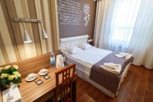- une petite chambre avec une table, un lit et un tableau noir dans l'établissement Motel Uyut, à Krutinka