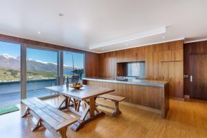 a kitchen with wooden cabinets and a table with benches at Luxe Home on the Hill in Queenstown