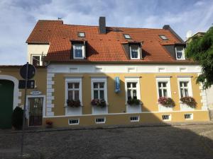 un bâtiment jaune et blanc avec un toit rouge dans l'établissement pension & sauna AM LORENZ, à Calbe