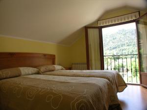 a bedroom with two beds and a large window at Apartamentos Puente La Molina in Carreña de Cabrales
