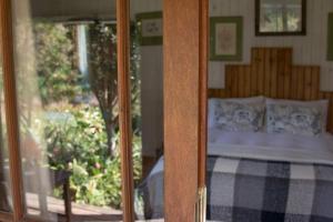 Puerta de cristal de un dormitorio con cama en Pear Tree Cottage, en Stormsrivier