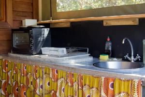a kitchen counter with a sink and a microwave at Pear Tree Cottage in Stormsrivier