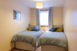 1 dormitorio con 2 camas y ventana en Modern apt, amazing harbour views, wifi & parking, en Musselburgh