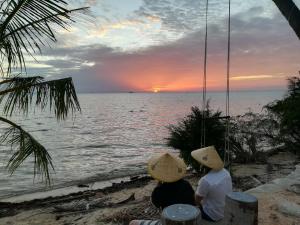 dos personas sentadas en la playa viendo la puesta de sol en The Ford SunSet Beach Resort, en Wok Tum