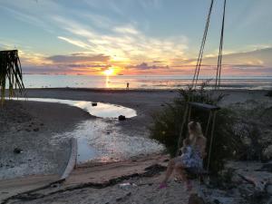 a woman sitting on a swing on the beach at sunset at The Ford SunSet Beach Resort in Wok Tum