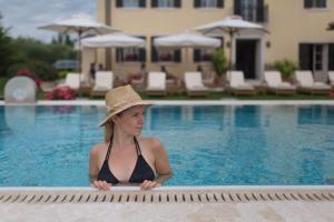 une femme dans un chapeau assise dans une piscine dans l'établissement ROMANTIK Relais d'Arfanta, à Tarzo