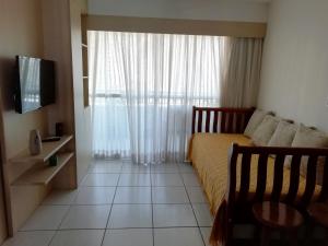 a bedroom with a bed and a tv and a window at Beach Class Rosalux in Fortaleza