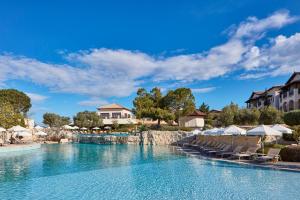 einen Pool in einem Resort mit Stühlen und Bäumen in der Unterkunft Atlantica Aphrodite Hills Hotel in Kouklia