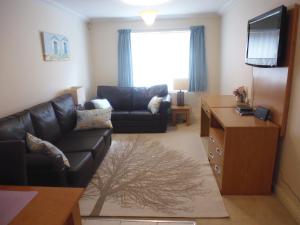 ein Wohnzimmer mit einem Ledersofa und einem TV in der Unterkunft Walking distance to beach , close to town center in Bournemouth