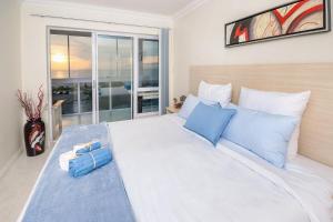 a bedroom with a large white bed with blue pillows at Main Beach Penthouse in Jeffreys Bay