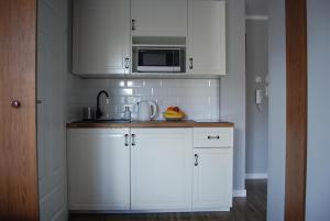 a kitchen with white cabinets and a microwave at Pałac Tatrzański-Apartament 206 in Bukowina Tatrzańska