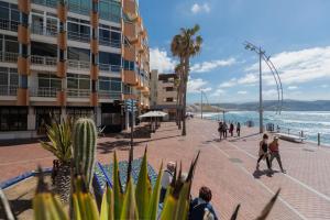 people walking on a sidewalk next to the beach at Apartamentos 306 -05 vista Teide in Las Palmas de Gran Canaria