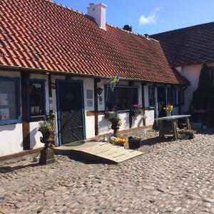 a building with a wooden porch and a table with flowers at Tunneberga Gästgifvaregård in Jonstorp