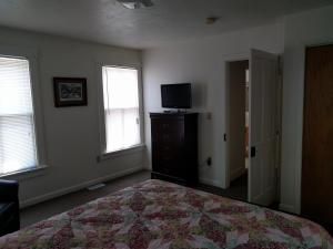 a bedroom with a bed and a tv and windows at Pearl's Place in Gettysburg