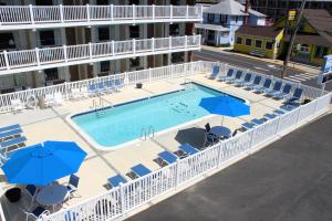 an outdoor swimming pool with chairs and umbrellas at Oceanus Motel - Rehoboth Beach in Rehoboth Beach