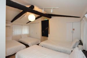 three beds in a room with white sheets at Kokon Higashiyama in Kyoto