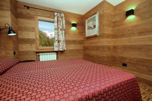 a bedroom with a red bed and a window at Champoluc Apartment in Champoluc