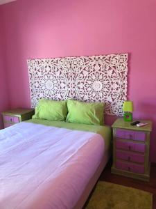 a bedroom with a large bed with a pink wall at Alojamento Local S. Bartolomeu in Trancoso