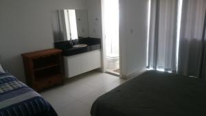 een slaapkamer met een bed en een badkamer met een wastafel bij Apartamentos Mirante de Escarpas in Capitólio