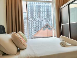 Soho Suites Klcc By Pnut KLCC VIEW في كوالالمبور: سرير مع وسائد و نافذة كبيرة مع مبنى