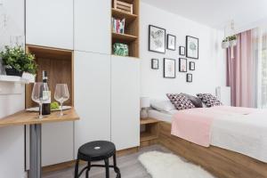 a bedroom with a bed and a table with a stool at City of the Kings - Pastel Apartment Lubelska 10 in Krakow