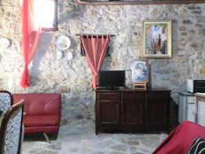un soggiorno con divano rosso e parete in pietra di La Bomboniera di Hanac a Pietrelcina