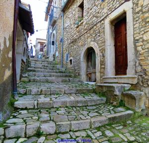 un callejón con escaleras de piedra y una puerta roja en La Bomboniera di Hanac, en Pietrelcina