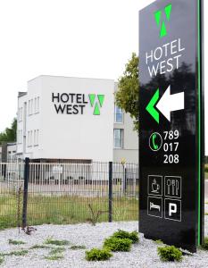 una señal frente a una señal de hotel frente a un edificio en Poznań West Hotel - Airport en Poznan