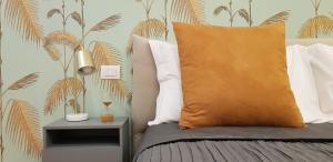 a bedroom with a bed with a orange pillow and a palm tree wallpaper at Serendipity Apartments - Duomo in Milan