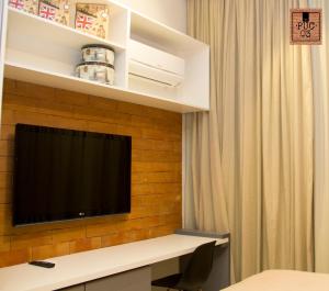 een hotelkamer met een televisie aan een bakstenen muur bij PUC 03 Itaipava RJ in Itaipava