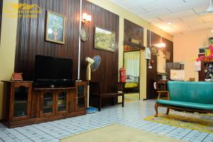 a living room with a tv and a blue chair at Teratak Ibunda Guest house in Kota Bharu