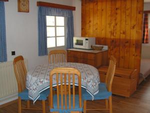 eine Küche mit einem Tisch, Stühlen und einer Mikrowelle in der Unterkunft Krkonosska Chalupa in Semily