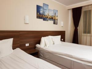 zwei Betten in einem Hotelzimmer mit weißen Laken in der Unterkunft Hotel Hermes in Alba Iulia