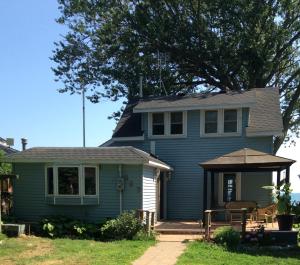 ein blaues Haus mit einer Veranda und einer Terrasse in der Unterkunft A Day at the Lake Cottage in Colchester