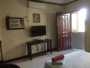 a bedroom with a bed and a television and a door at Sunrise Apartelle in Olongapo