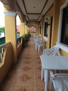 un patio con mesas blancas y sillas en el balcón en Sunrise Apartelle en Olongapo