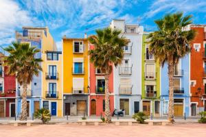 a row of colorful apartment buildings with palm trees at Stylish Apartment in Villajoyosa