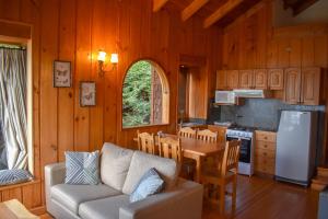 eine Küche und ein Wohnzimmer mit einer Couch und einem Tisch in der Unterkunft Cabañas Monte Verde in Pucón