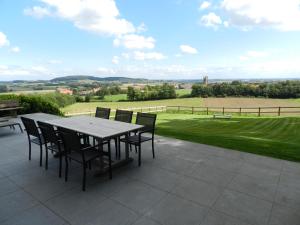 a table and chairs on a patio with a view of a field at Fleur d’ Amour in Heuvelland