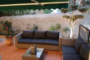 un patio con sofá, mesa y pared en 23 Rue Jean Amade, en Céret