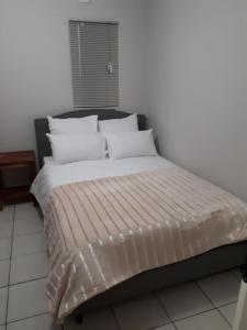 1 cama con sábanas blancas y almohadas en una habitación en Dreamwood Guest House en Nelspruit