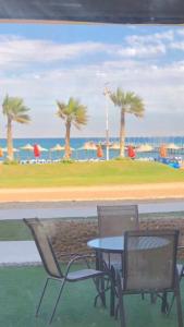 a table and chairs with palm trees in the background at Chalet Porto South Beach - Beach Front Sea View in Ain Sokhna